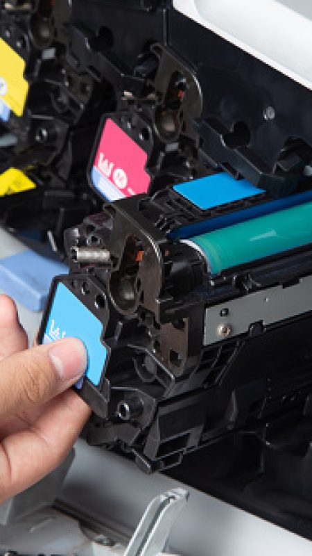 Business man or technician is checking and changing the printer equipment cartridges tone of laser jet multi function printer in the office. Close-up shot of CMYK ink cartridges for laser printer.